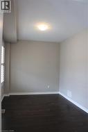 Room featuring dark wood-finish flooring, light-toned walls, and white trim molding - 