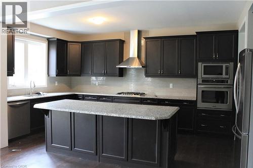 Modern kitchen featuring dark wood-finish cabinetry, light-toned countertops, a full suite of stainless steel appliances, a tiled backsplash, and recessed lighting - 31 Pointer Street Unit# Main Floor, Cambridge, ON - Indoor Photo Showing Kitchen With Double Sink