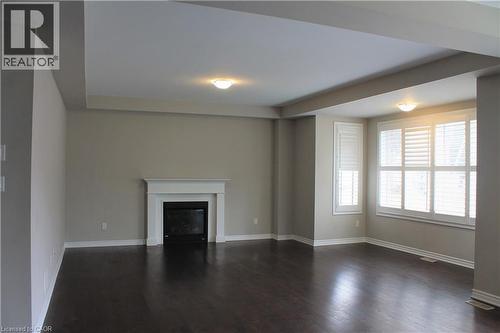 Spacious room featuring dark wood-finish flooring, a white mantel fireplace, and multiple windows with plantation shutters - 31 Pointer Street Unit# Main Floor, Cambridge, ON - Indoor With Fireplace