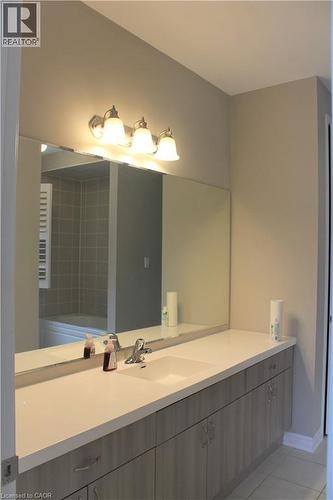 Long vanity featuring an integrated sink, brushed nickel faucet, and wood-finish cabinetry - 31 Pointer Street Unit# Main Floor, Cambridge, ON - Indoor Photo Showing Bathroom