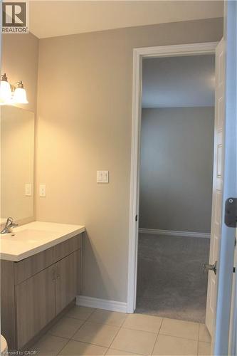 Bathroom vanity featuring a light wood-finish cabinet with double doors, an integrated countertop sink, and a mirrored backsplash - 31 Pointer Street Unit# Main Floor, Cambridge, ON - Indoor Photo Showing Bathroom