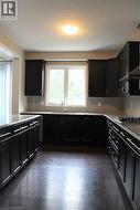 Kitchen featuring dark wood-finish cabinetry and dark countertops - 