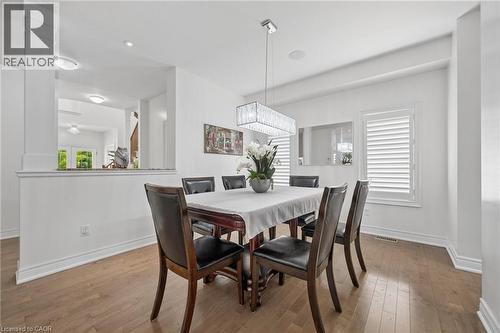 Dining area featuring wood-finish flooring, white walls, and a crystal chandelier - 145 Redtail Street, Kitchener, ON - Indoor Photo Showing Dining Room