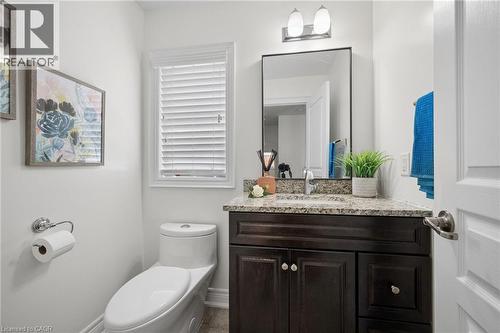 Powder room featuring a dark wood-finish vanity with a granite countertop, undermount sink, and a rectangular mirror - 145 Redtail Street, Kitchener, ON - Indoor Photo Showing Bathroom