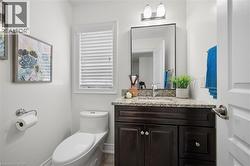 Powder room featuring a dark wood-finish vanity with a granite countertop, undermount sink, and a rectangular mirror - 