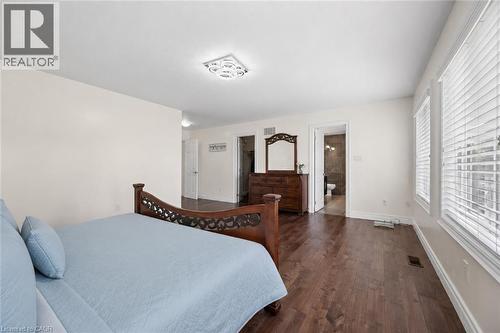 Spacious bedroom featuring wood-finish flooring, light-toned wall paint, and multiple windows with blinds - 145 Redtail Street, Kitchener, ON - Indoor Photo Showing Bedroom