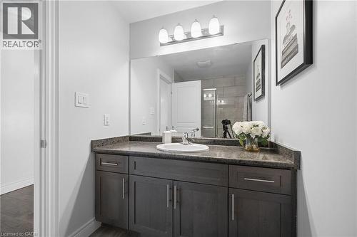 Bathroom vanity featuring a dark wood-finish cabinet, speckled countertop, and integrated sink - 145 Redtail Street, Kitchener, ON - Indoor Photo Showing Bathroom