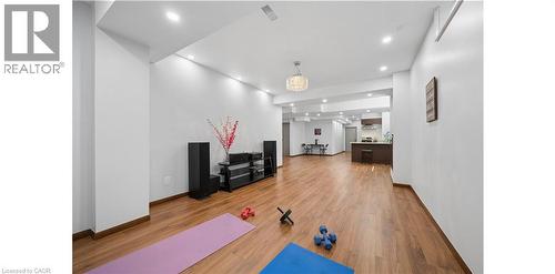 Spacious open-concept living area featuring wood-finish flooring, recessed lighting, and a contemporary chandelier - 145 Redtail Street, Kitchener, ON - Indoor Photo Showing Other Room