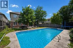 Expansive backyard featuring an in-ground swimming pool with stone coping and stainless steel ladder - 