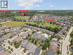 Aerial view showcasing a residential neighborhood with detached homes, green spaces, and a tree-lined perimeter - 