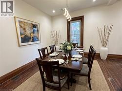 Dining area featuring wood-finish flooring, white walls, and dark wood trim - 