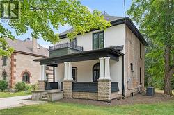 Stucco and stone exterior with a covered porch featuring decorative pillars and a second-story balcony with wrought iron railing - 