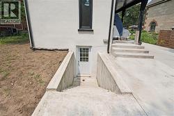 Exterior entrance featuring a white door with grid-pane window, concrete steps, and concrete retaining walls - 