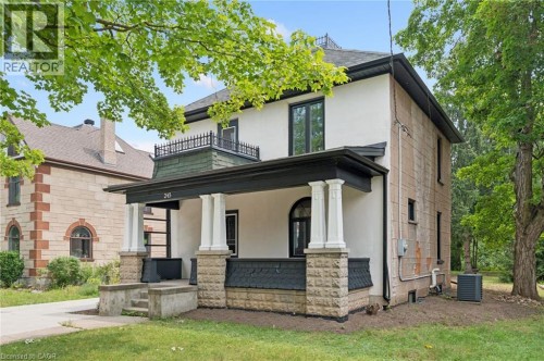 Stucco and stone exterior with a covered porch featuring decorative pillars and a second-story balcony with wrought iron railing - 245 Lowther Street S, Cambridge, ON - Outdoor With Deck Patio Veranda