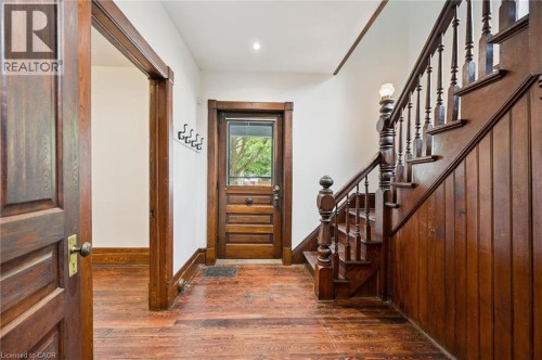 Foyer featuring wood-finish flooring, a traditional wood staircase with balusters, wood paneling, a wood entry door with glass upper portion, and wood trim - 245 Lowther Street S, Cambridge, ON - Indoor Photo Showing Other Room