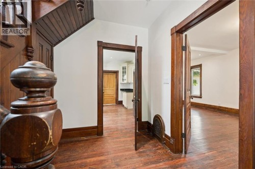 Hardwood flooring throughout featuring dark wood trim and doors, a detailed staircase banister, and white wall finishes - 245 Lowther Street S, Cambridge, ON - Indoor Photo Showing Other Room