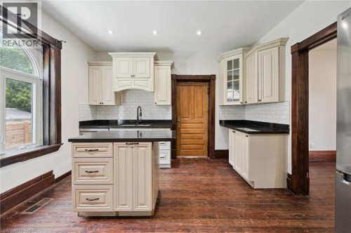 Kitchen featuring an island, black countertops, cream cabinetry, subway tile backsplash, and wood-finish flooring - 245 Lowther Street S, Cambridge, ON - Indoor Photo Showing Kitchen