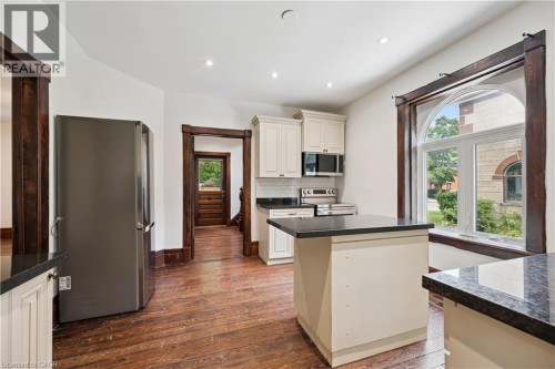 Kitchen featuring cream-colored cabinetry, black countertops, stainless steel appliances, and wood-finish flooring - 245 Lowther Street S, Cambridge, ON - Indoor Photo Showing Kitchen