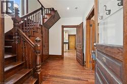 Foyer featuring wood-finish flooring, a traditional wood staircase with balusters, wood paneling, - 