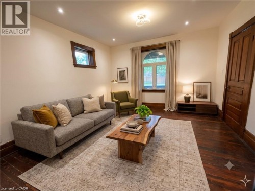 Living area showcasing dark wood-finish flooring, a large arched window with trim, and a paneled door - 245 Lowther Street S, Cambridge, ON - Indoor Photo Showing Living Room