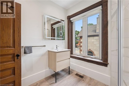 Modern bathroom featuring a vanity with integrated sink, illuminated mirror, and wood-finish flooring - 245 Lowther Street S, Cambridge, ON - Indoor