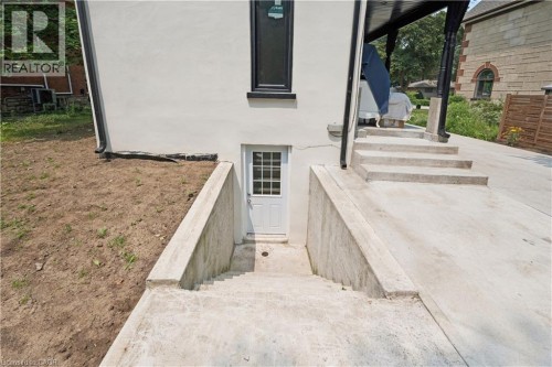 Exterior entrance featuring a white door with grid-pane window, concrete steps, and concrete retaining walls - 245 Lowther Street S, Cambridge, ON - Outdoor With Exterior