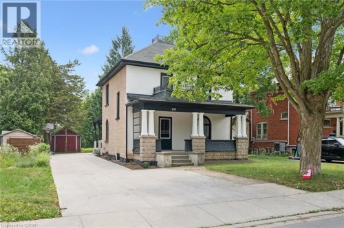 Two-story residence featuring a covered front porch with substantial columns, a light-colored brick facade, and a dark roof - 245 Lowther Street S, Cambridge, ON - Outdoor With Facade