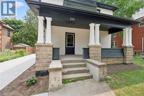 Stucco and stone exterior with a covered porch featuring decorative pillars and a second-story balcony with wrought iron railing - 245 Lowther Street S, Cambridge, ON - Outdoor