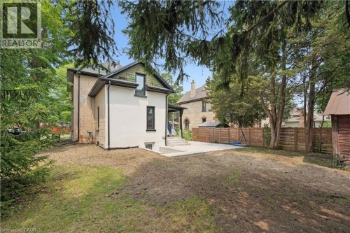 Spacious rear yard with a concrete patio, wood fence, mature trees, and a detached shed - 245 Lowther Street S, Cambridge, ON - Outdoor