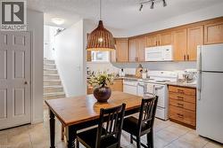 Kitchen with light wood-finish cabinetry, white appliances, and a track lighting fixture - 