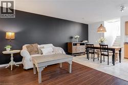 Open-concept living space with dark accent wall, wood-finish flooring, and a dining area featuring a woven pendant light - 