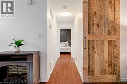 Hallway featuring wood-finish flooring, white walls, and a recessed ceiling light - 