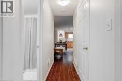 Hallway featuring wood-finish flooring, white walls, and a flush mount ceiling light - 