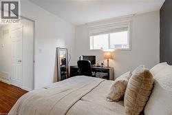 Bedroom featuring a window with blinds, white walls, and wood-finish flooring - 