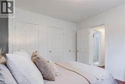 Bedroom with white walls and dark accent wall, featuring multiple panel doors with brass hardware, and an en-suite bathroom entrance - 