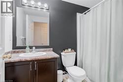 Bathroom featuring a dark wood-finish vanity with a built-in sink, speckled countertop, and a large mirror - 