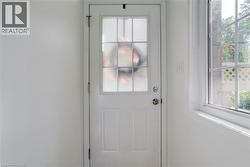 Entry door with upper paneled glass, complemented by a multi-pane window featuring grid accents - 