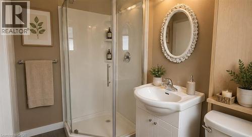 Bathroom featuring a glass-enclosed shower, white vanity with integrated sink, oval framed mirror, and a toilet with a wood-finish shelf above - 274 East 38Th Street, Hamilton, ON - Indoor Photo Showing Bathroom