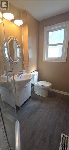 Bathroom featuring wood-finish flooring, a white vanity with an integrated sink, an ornate framed mirror, and a white toilet - 274 East 38Th Street, Hamilton, ON - Indoor Photo Showing Bathroom