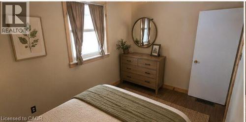 Interior room featuring a window with natural wood trim, wood-finish flooring, and light-toned walls - 274 East 38Th Street, Hamilton, ON - Indoor