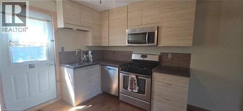 Kitchen featuring light wood-finish cabinetry, stainless steel appliances, dark countertops, and a mosaic tile backsplash - 274 East 38Th Street, Hamilton, ON - Indoor Photo Showing Kitchen