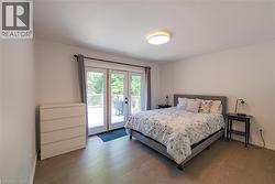 Room featuring wood-finish flooring, a contemporary ceiling light fixture, and white walls - 