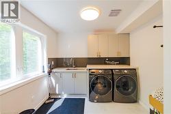 Utility room featuring a window, built-in cabinetry, countertop, and a sink with a faucet - 