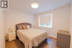 Well-lit interior space featuring wood-finish flooring, light-toned walls, and a window with a roller shade - 
