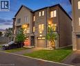 Contemporary townhome featuring a brick and stone facade, private driveway, integrated garage, and a second-story balcony with glass railing - 16 Raspberry Lane, Hamilton, ON  - Outdoor 