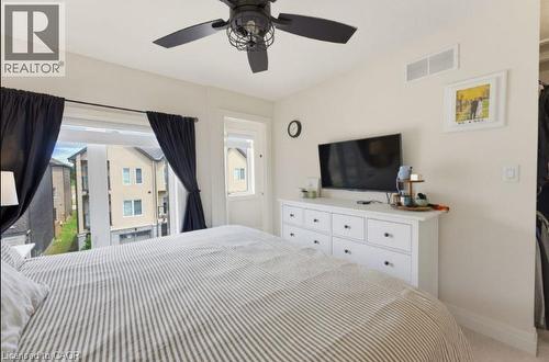 Spacious room with a ceiling fan featuring a cage light kit, multiple windows, and light-toned walls - 16 Raspberry Lane, Hamilton, ON - Indoor Photo Showing Bedroom