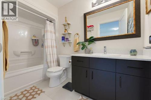 Modern bathroom featuring a dark vanity with a light countertop, an undermount sink, and a large framed mirror - 16 Raspberry Lane, Hamilton, ON - Indoor Photo Showing Bathroom