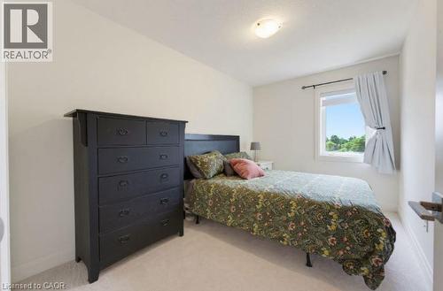 Bedroom featuring light-colored walls, ceiling-mounted light fixture, white window trim, and light-colored carpeting - 16 Raspberry Lane, Hamilton, ON - Indoor Photo Showing Bedroom