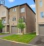 Modern townhouse exterior featuring a brick facade with stone accents, a single-car garage, and a small balcony with black railings - 16 Raspberry Lane, Hamilton, ON  - Outdoor 