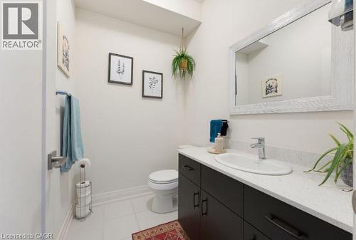 Bathroom featuring white tiled flooring, a dark wood-finish vanity with an integrated basin, a light-colored countertop, and a large framed mirror - 16 Raspberry Lane, Hamilton, ON - Indoor Photo Showing Bathroom